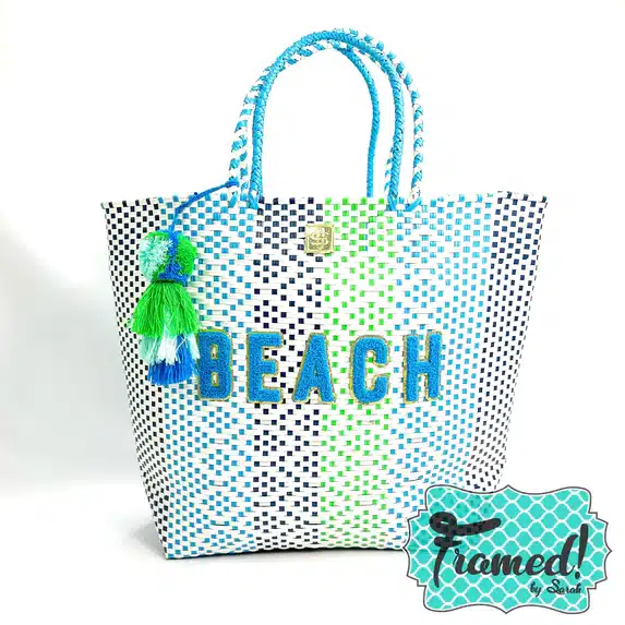 black, aqua, and green striped tote with a tassel and the word Beach on the front