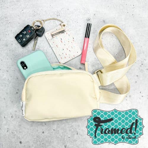 ivory belt bag on a marble backgroud display with a mint cell phone, lip gloss, keys, and other accessories