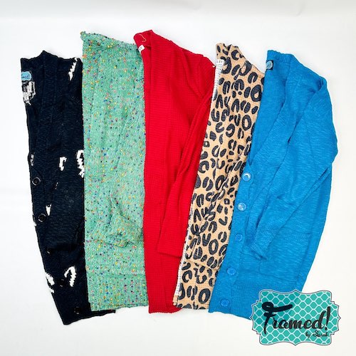 5 colorful Cardigans displayed on a white backdrop. In order, black with white hearts, green, red, leopard, blue