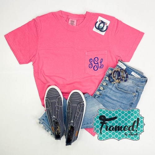 Hot pink t-shirt with a blue monogram on the chest pocket styled with jeans and blue sneakers