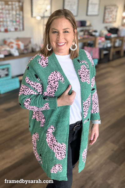 Woman wearing green cardigan with pink leopard pattern, white tshirt and black jeans